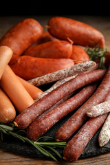Different tasty sausages on wooden table, closeup
