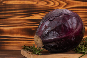 Fototapeta na wymiar Purple cabbage and rosemary on cutting board, wooden background. Fresh vegetables, healthy organic food concept