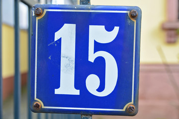 A house number plaque, showing the number fifteen (15)