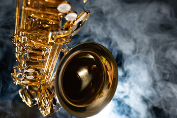 Golden shiny alto saxophone on black background with smoke. copy space - obrazy, fototapety, plakaty