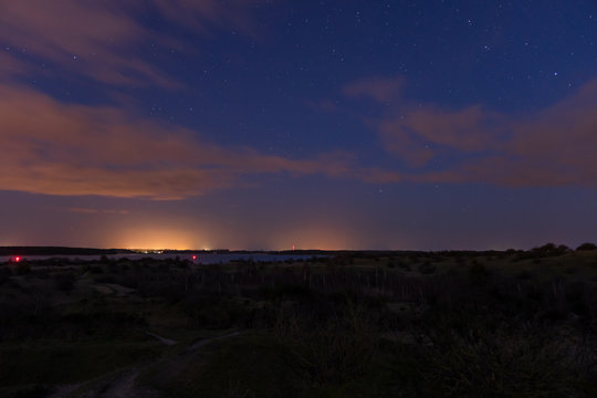 Landscape shot of the night sky with stars and clouds captured on the hilly peninsula Devin near Stralsund and Ruegen with the ocean in the background