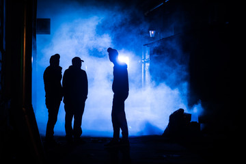 Silhouettes of people in the night on a blue background in the fog