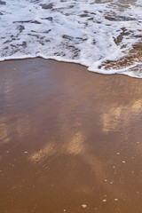 White foam on a sandy beach. Copy space.