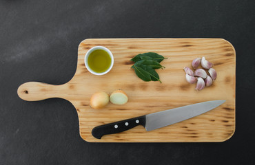 Fresh vegetables, knife and olive oil on wooden background