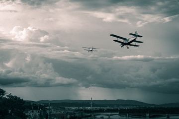 Fototapeta na wymiar Two old biplanes flying in the stormy sky of Budapest, Hungary