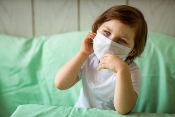 a little girl, wearing a medical mask, plays at home, in home quarantine, during the coronavirus pandemic,COVID-2019