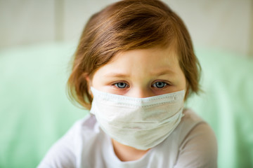 a little girl, wearing a medical mask, plays at home, in home quarantine, during the coronavirus pandemic,COVID-2019