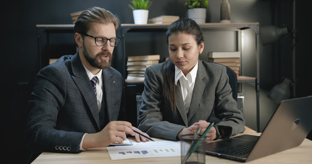 Businesspeople discussing work. Experienced male worker gives instructions to newcomer showing chart