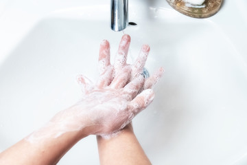 Washing hands with soap under the faucet with water
