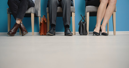 Fototapeta na wymiar Cropped picture of three job applicants sitting on chairs in corridor waiting for audition