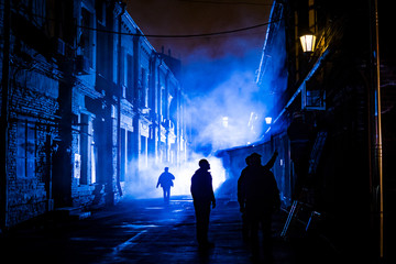 Silhouettes of people in the night on a blue background in the fog