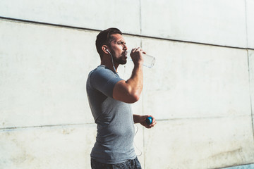 Strong guy drinking water resting after run in street