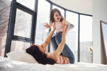 Young mother with her daughter have fun at weekend time together on bed