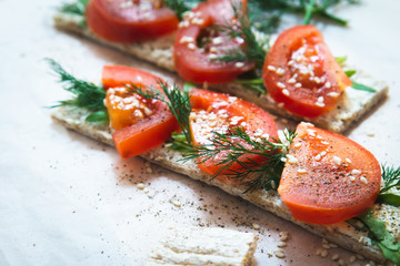 toast with cream cheese and with fresh tomatoes and herbs on a light background. Sandwiches with...