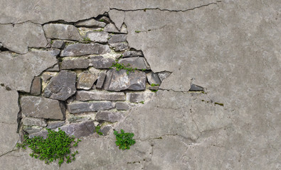 An old wall of stones of different sizes with crumbling plaster.