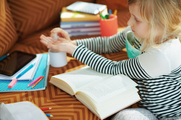 child with medical mask with reading book and sanitizes hands