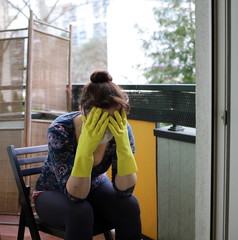 A woman wearing a protective mask on the balcony of her home