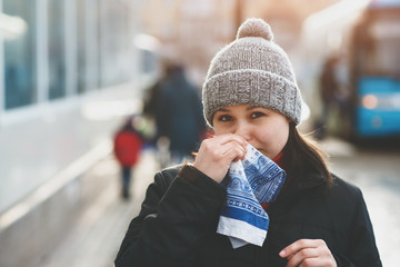 a young woman uses a handkerchief during a runny nose, in the cold season.