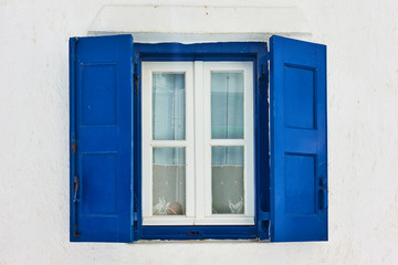 Fototapeta na wymiar Window with blue shutters in Mykonos
