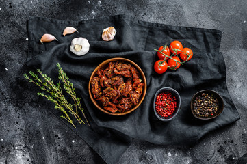 Dried tomatoes with garlic, spices and herbs. Recipe for cooking with ingredients. Black, dark background. Top view