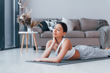 Lying down on the mat and taking a break. Young woman with slim body shape in sportswear have...