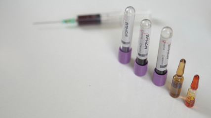 Coronavirus test tubes, flasks in laboratory with scientist background.