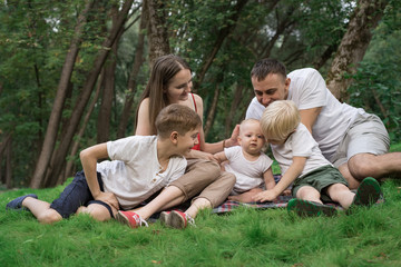 Naklejka na ściany i meble Young family with three children outdoors. Big happy family resting in nature