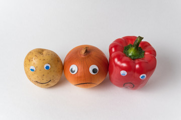 Potatoes, onions and peppers with funny faces. White background top view. concept is different from the others