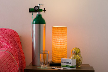 Oxygen cylinder with cannula and a box of Paracetamol tablets next to the bed