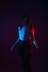 Fototapeta na wymiar Blue and red light portrait of a female model on a black background with high contrast