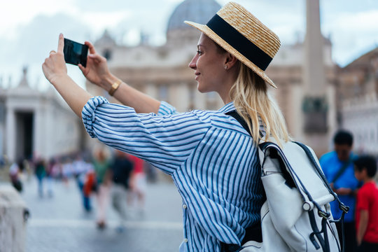 Attractive female in trendy apparel clicking pictures via modern cellphone camera with high quality of photographing, carefree tourist shooting vlog content about Italian vacation in Vatican