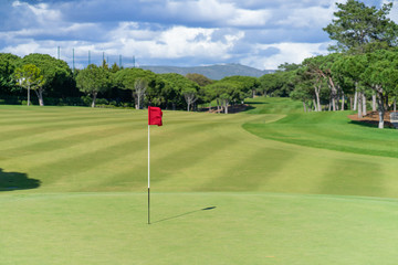 Obraz premium Beautiful golf course in summer with red golf flag and green grass