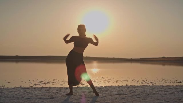 young dancing girl by the lake in sunset