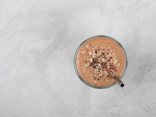 Smoothie from dates, nuts, chocolate in a glass on a light gray background top view