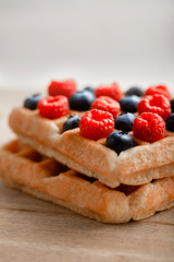 Tasty waffles with raspberries, blueberries and strawberries on the top.