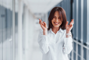 Brunette in white shirt posing indoors in modern airport or hallway at daytime