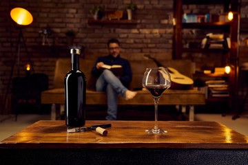 Glass of red wine on table at home man reading