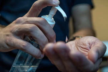 A tan hairy arm person squirts sanitizer on their hands to kill any lingering germs from the objects they had touched throughout the work day to protect themselves from viruses and other diseases.