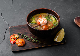 Chinese dishes in a clay plate on a black concrete background with ingredients for delivery