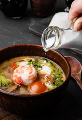 Chinese dishes in a clay plate on a black concrete background with ingredients for delivery