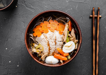 Chinese dishes in a clay plate on a black concrete background with ingredients for delivery
