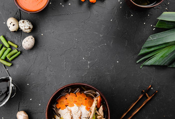 Chinese dishes in a clay plate on a black concrete background with ingredients for delivery