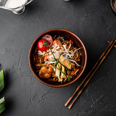 Chinese dishes in a clay plate on a black concrete background with ingredients for delivery