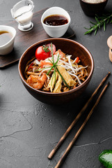 Chinese dishes in a clay plate on a black concrete background with ingredients for delivery