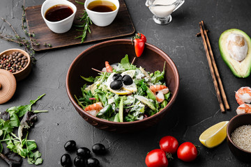 Chinese dishes in a clay plate on a black concrete background with ingredients for delivery