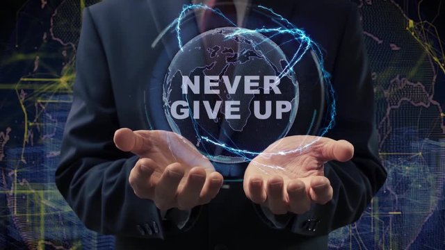 Male hands activate a conceptual holographic text Never give up. Businessman in a suit with a hologram of planet Earth on a background of a futuristic wireframe city