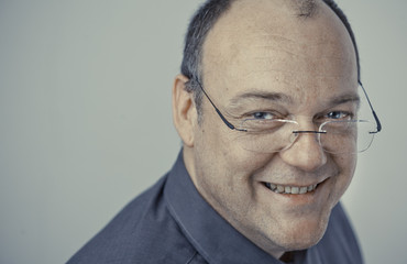 Older man with glasses and bald head looking joyful