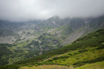 Some people walking down the slope among misty mountains.