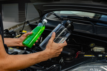 Topic of car repair shop: hands showing choice of coolant or water for car coolant system....