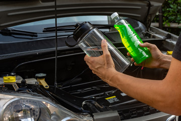  Topic of car repair shop: hands  showing choice of coolant or water for car coolant system....